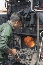 Shoving coal into the steam locomotive of Darjeeling Himalayan Railway
